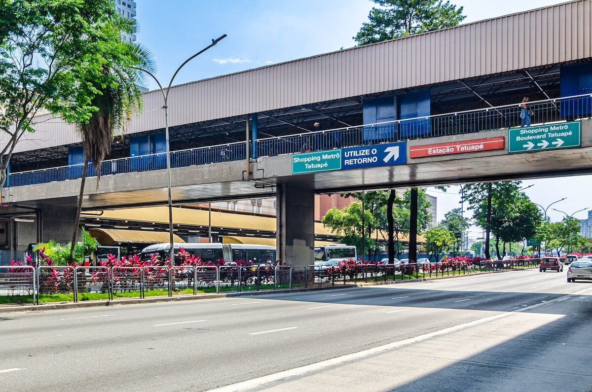 Rua junto a estacao Tatuape, com o viaduto da estacao, onibus embaixo e canteiro florido na calcada